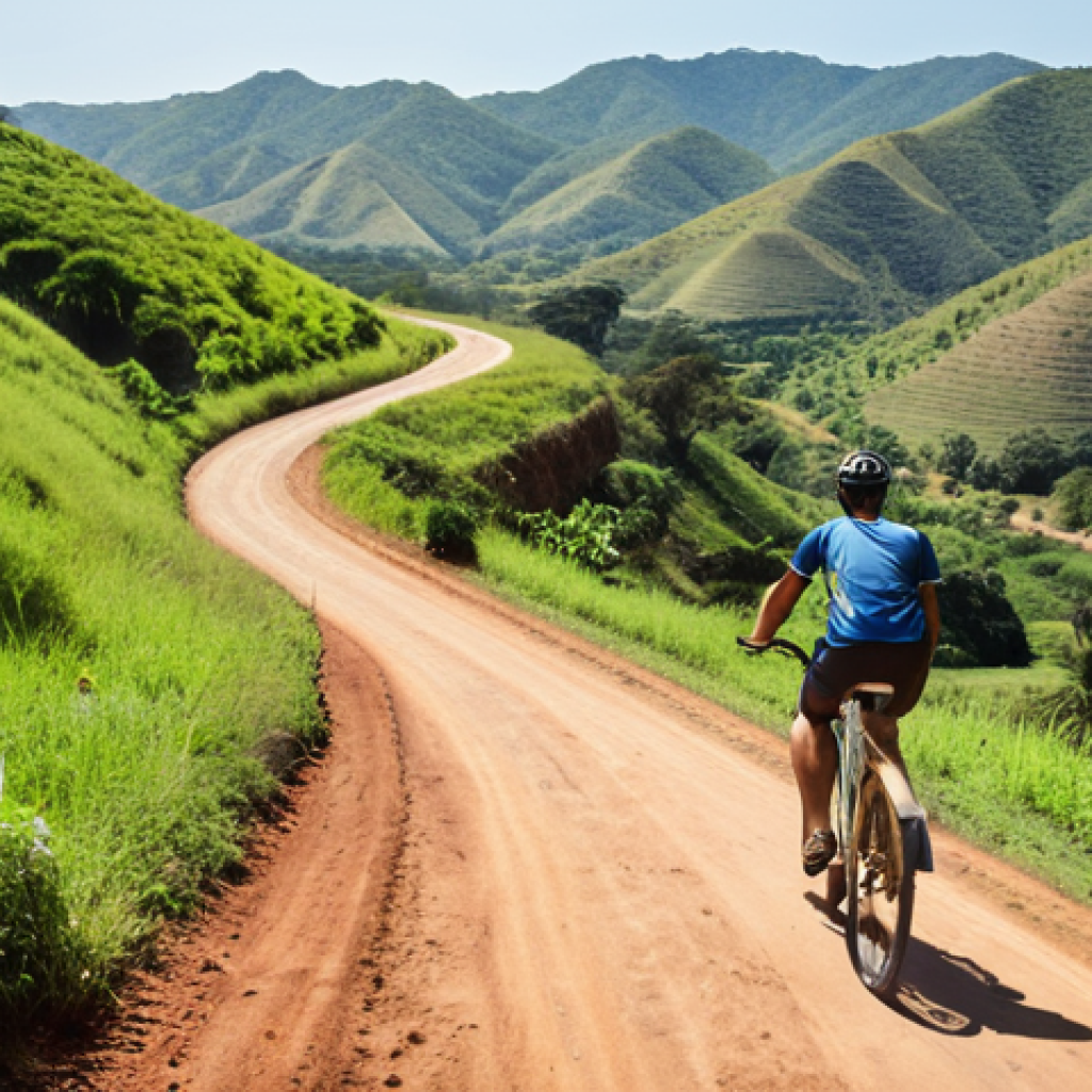**A cyclist riding a bicycle on a winding dirt road through the lush, green hills of Eswatini. In the background, rolling hills and valleys stretch out under a bright sky. Focus on the sense of adventure and freedom.**